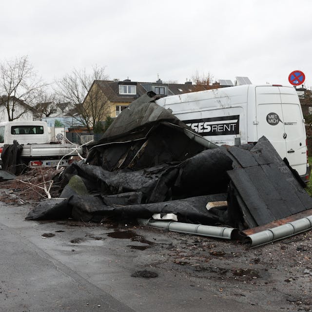 Ein abgedecktes Dach ist auf eine Straße in Köln-Poll geweht worden und liegt vor einem Kleintransporter.