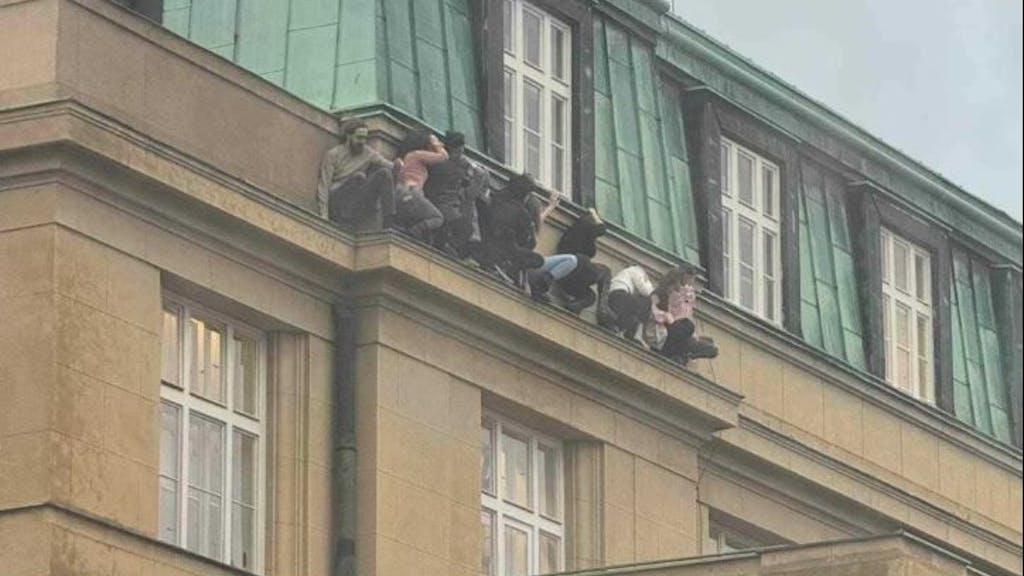 Angriff in Prag: Erschütternde Bilder zeigen junge Menschen, die auf einem schmalen Sims an der Fassade des Gebäudes zusammenkauerten, während sie Schutz vor dem Schützen suchten.