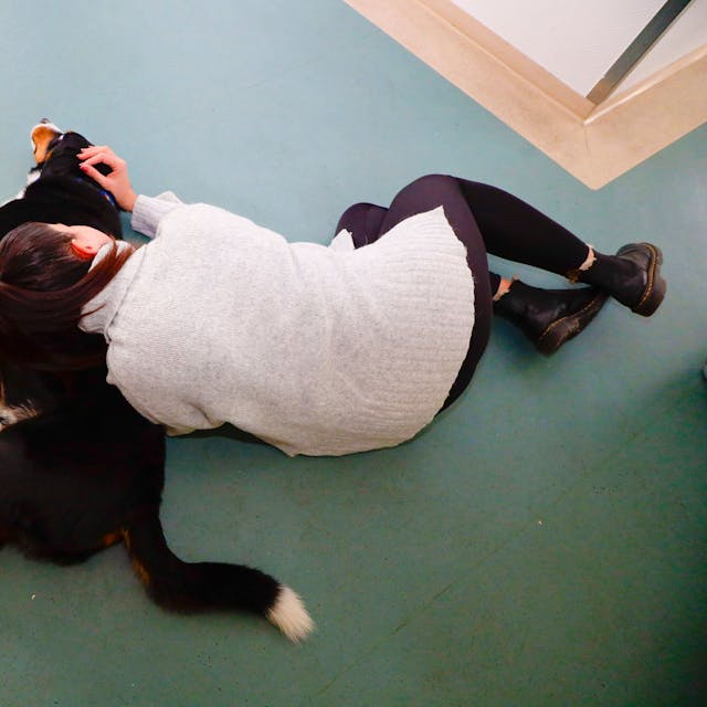 Therapiehund Rico der.Jugendpsychiatrie Holweide liegt mit einer Patientin auf dem Boden.
