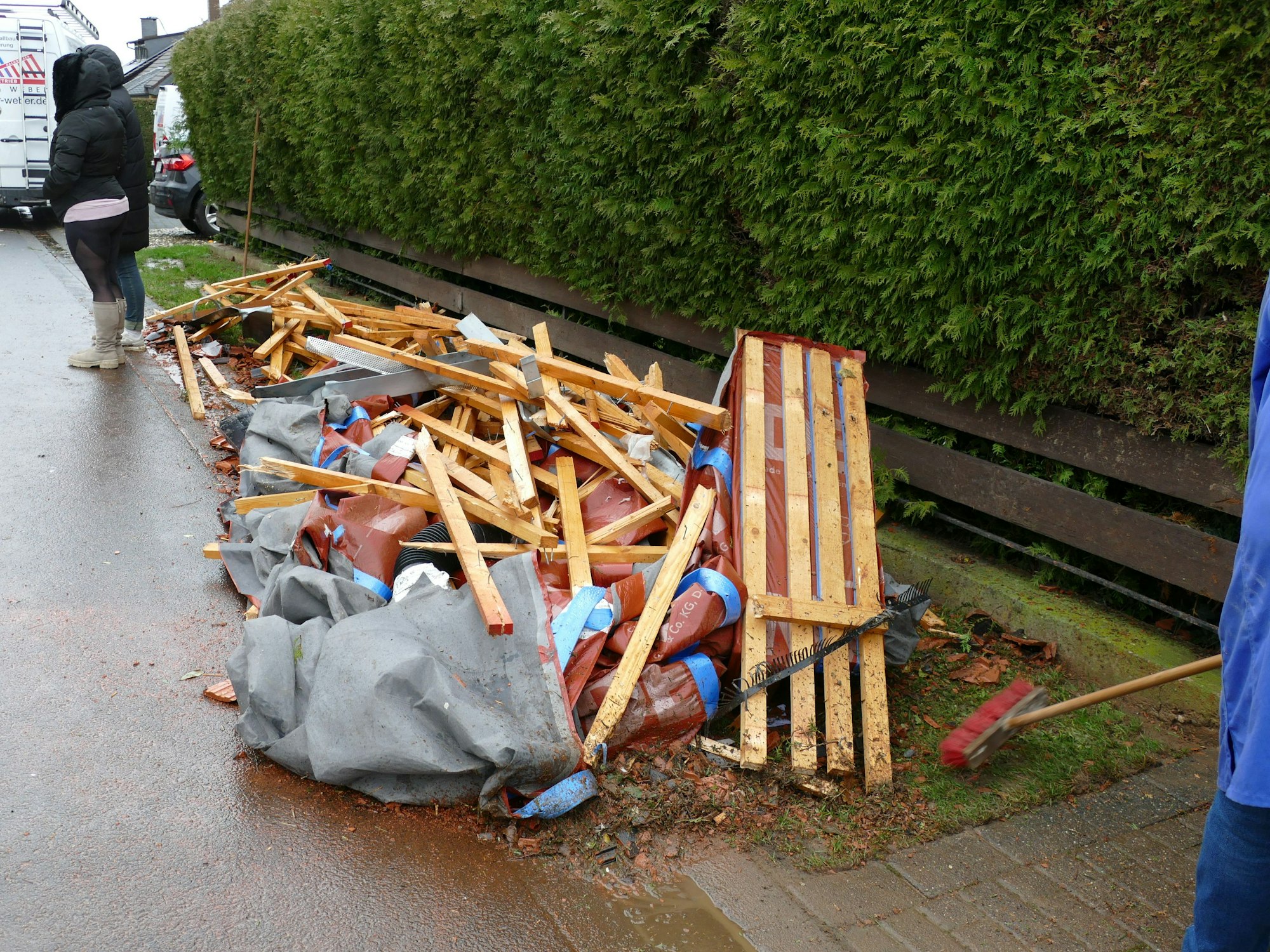 Ein Haufen Schutt aus Holz, Planen und Plastik liegt an einer Straße.
