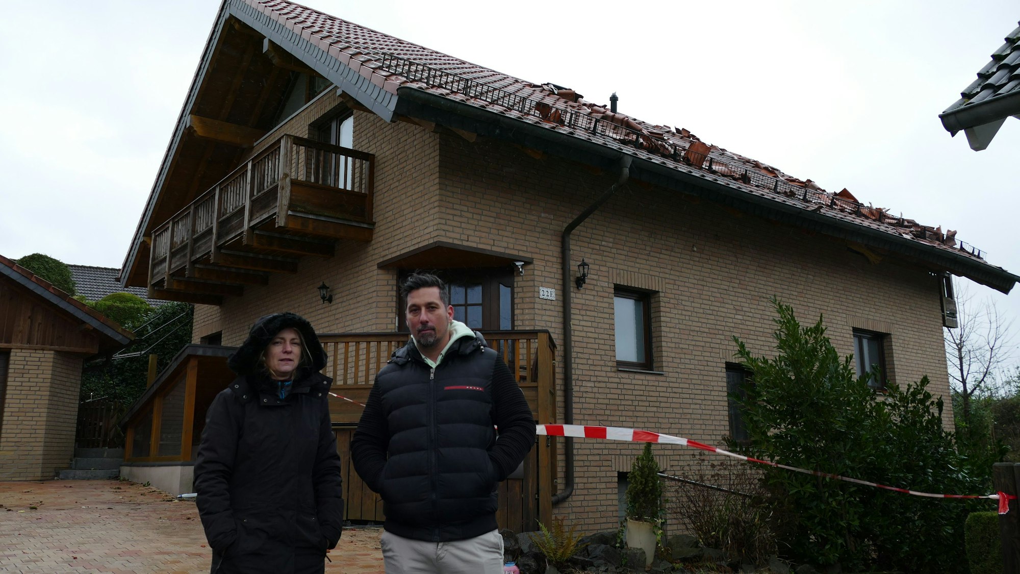 Christine und Florian Staubach vor ihrem Haus in der Dorfstraße in Lohmar-Krahwinkel, dessen Dach komplett zerstört ist. Hinein dürfen sie nicht mehr.