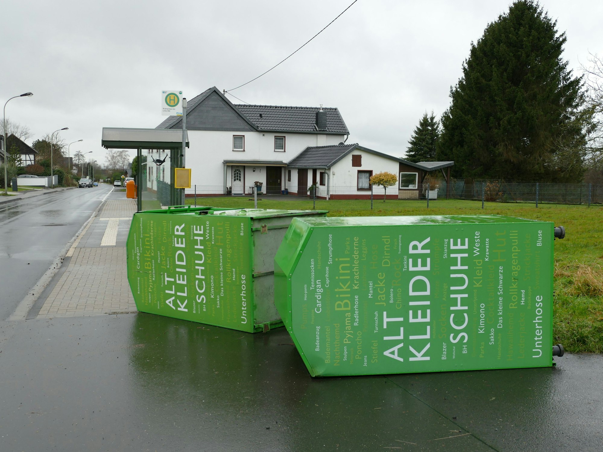 Zwei grüne Alt-Kleider-Container liegen umgekippt auf dem Gehweg.