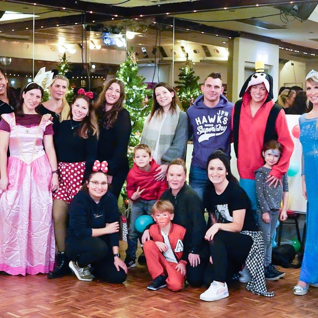 Frauen, Männer und Kinder, teils in Kostümen, posieren für ein Gruppenfoto.