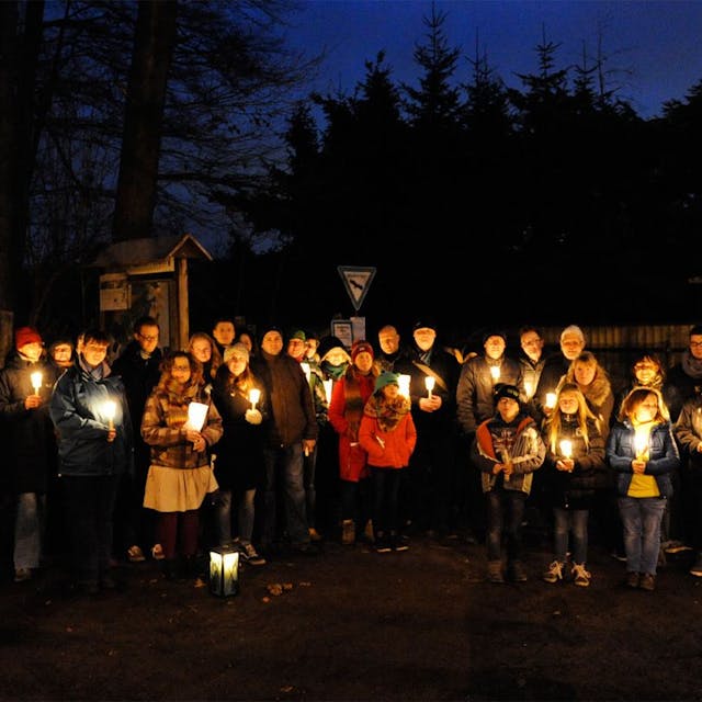 Zu sehen sind die Teilnehmer der Wanderung, die Kerzen in den Händen halten.