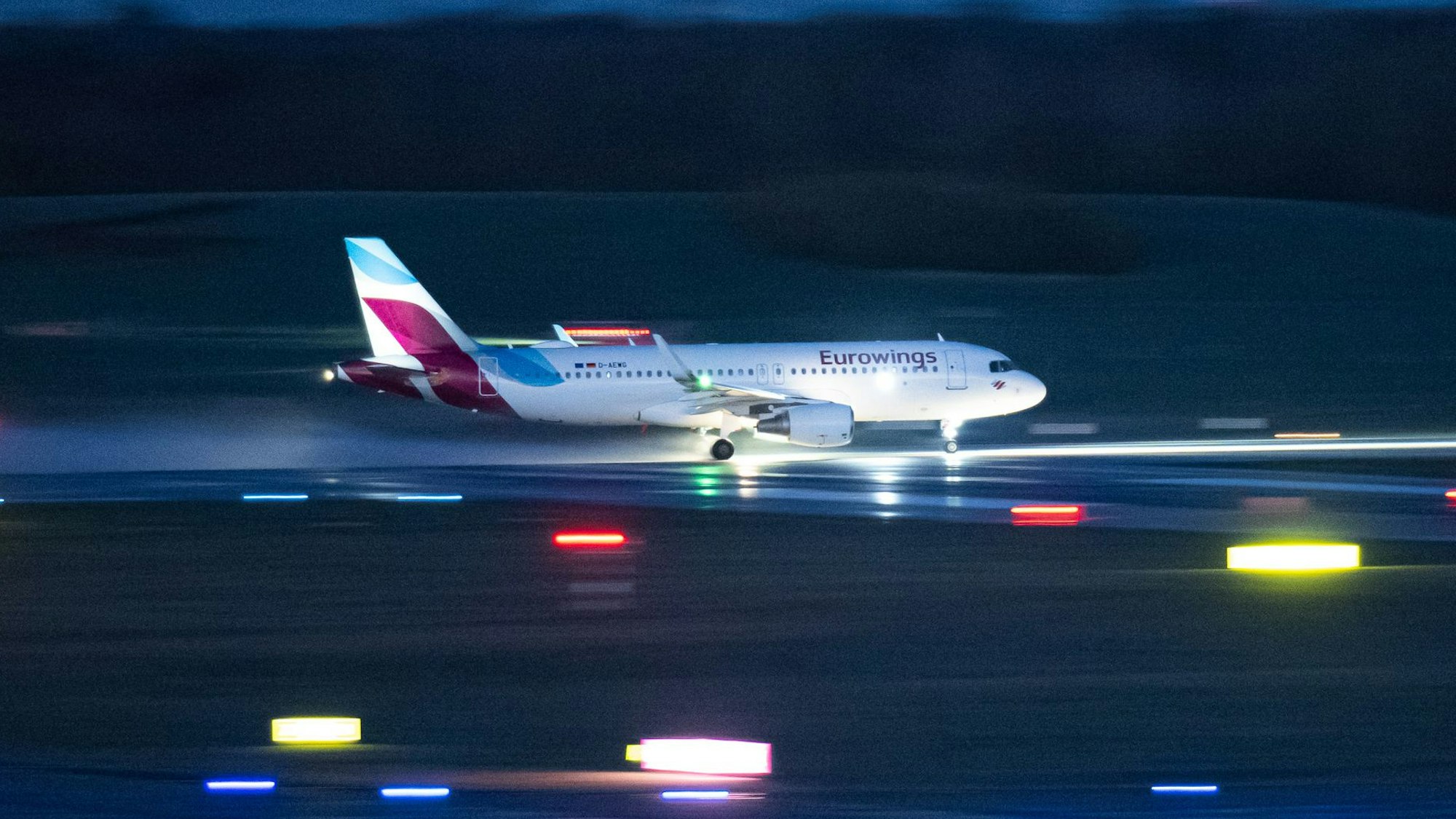 Ein Airbus A320 der deutschen Fluggesellschaft Eurowings landet auf einer beleuchteten Landebahn. Mehrere Warnleuchten sind aktiv. (Symbolbild)