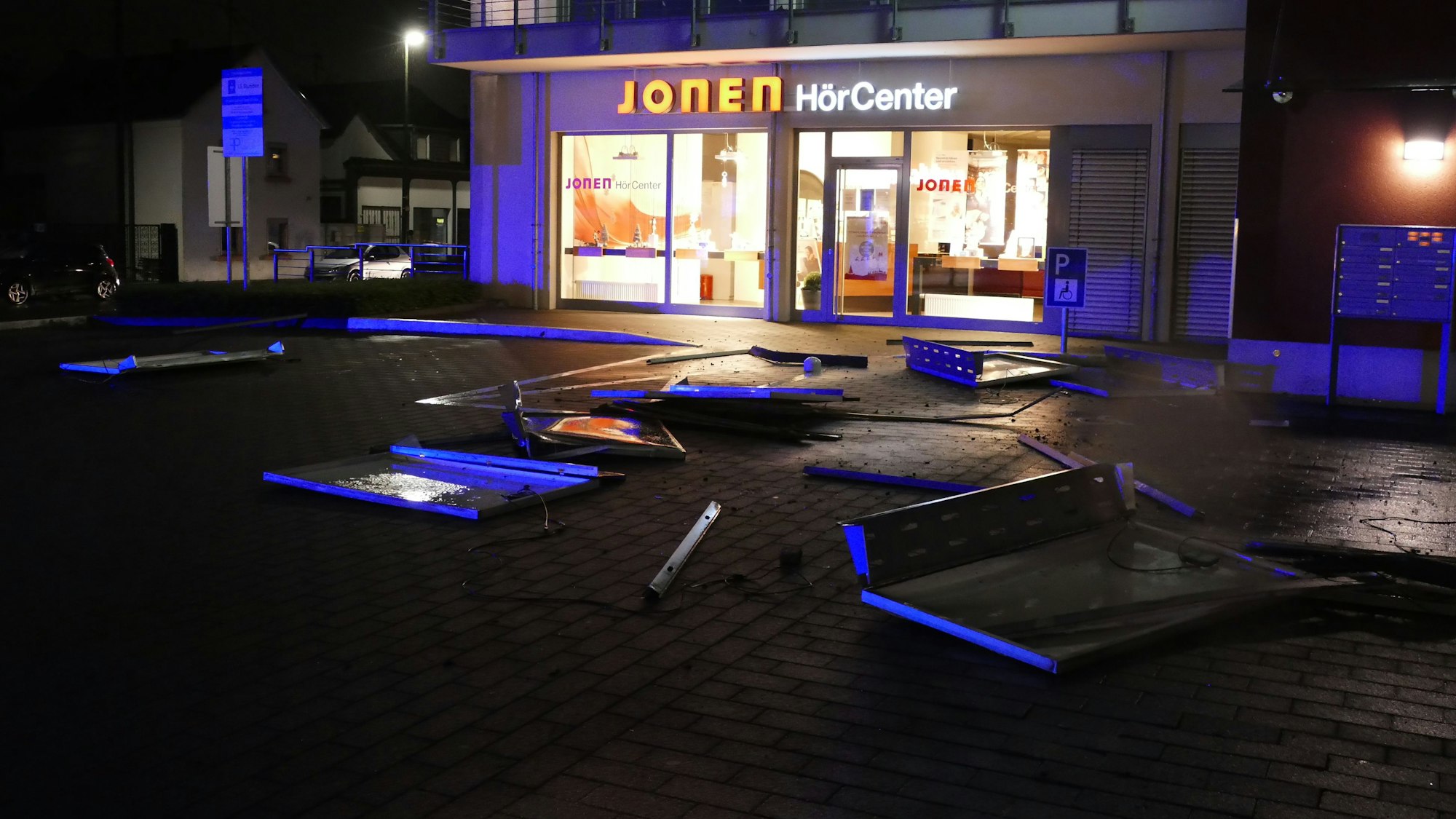 Teile einer Photovoltaik-Anlage liegen verbogen und zerstört auf dem Boden vor einem Geschäft in Sankt Augustin