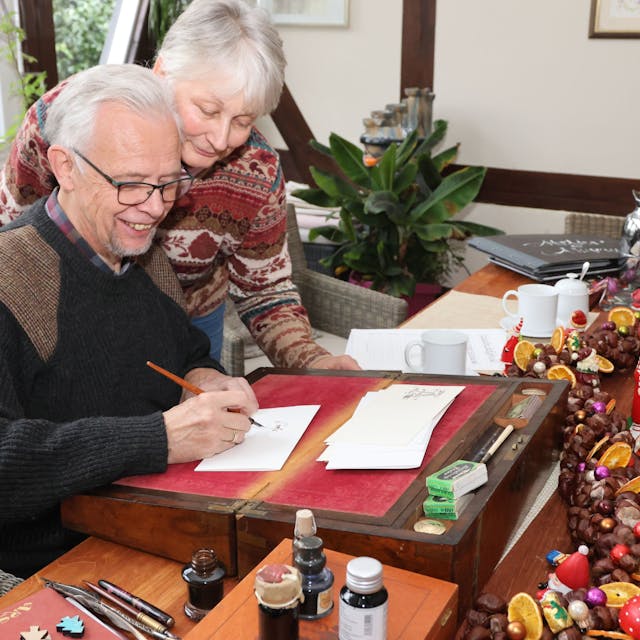 Ein Mann und eine Frau schreiben gemeinsam einen Weihnachtsbrief.