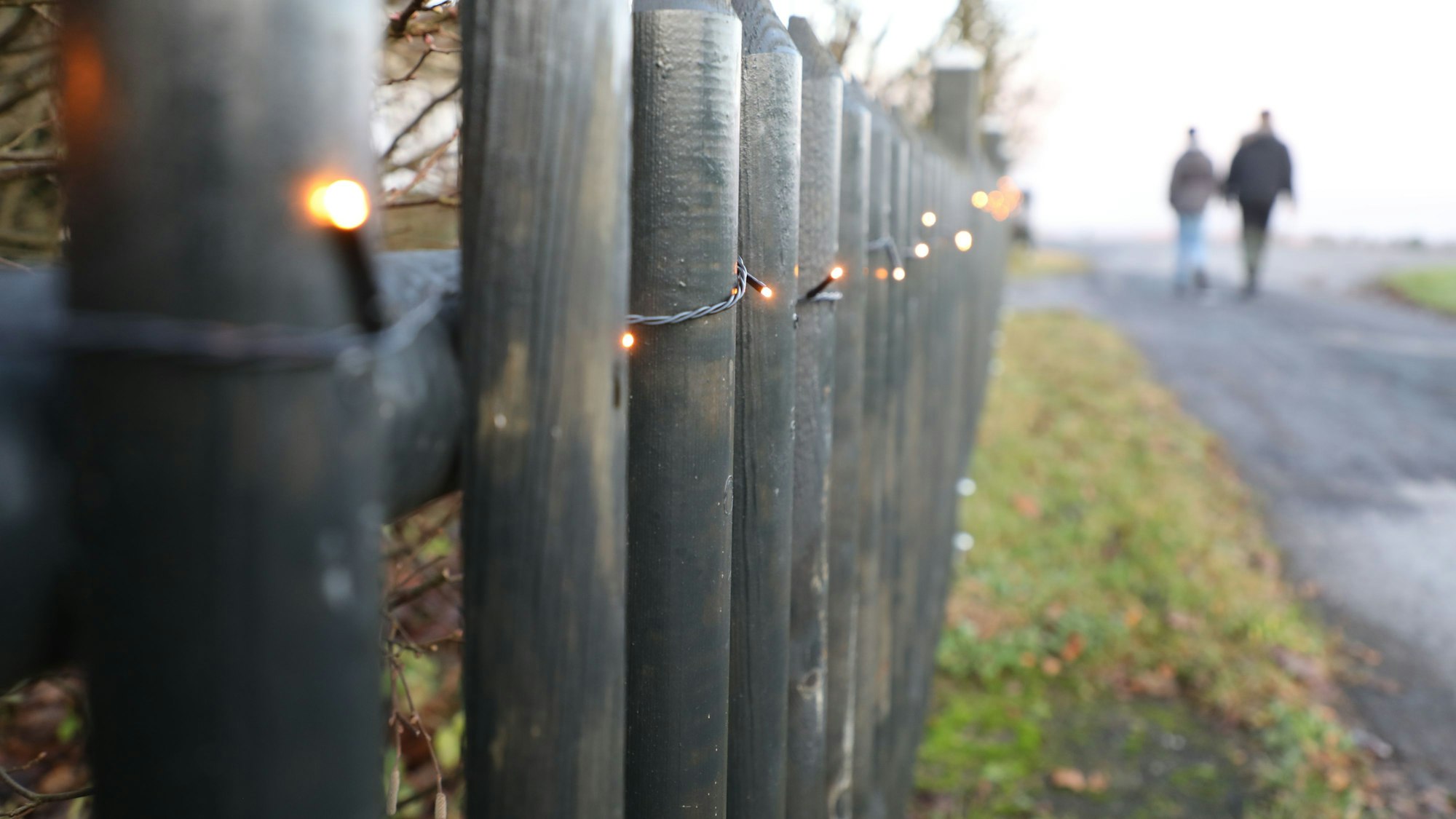 Lichter am Weg an einem weihnachtlich geschmückten Zaun bei Bergisch Gladbach-Hasselsheide.