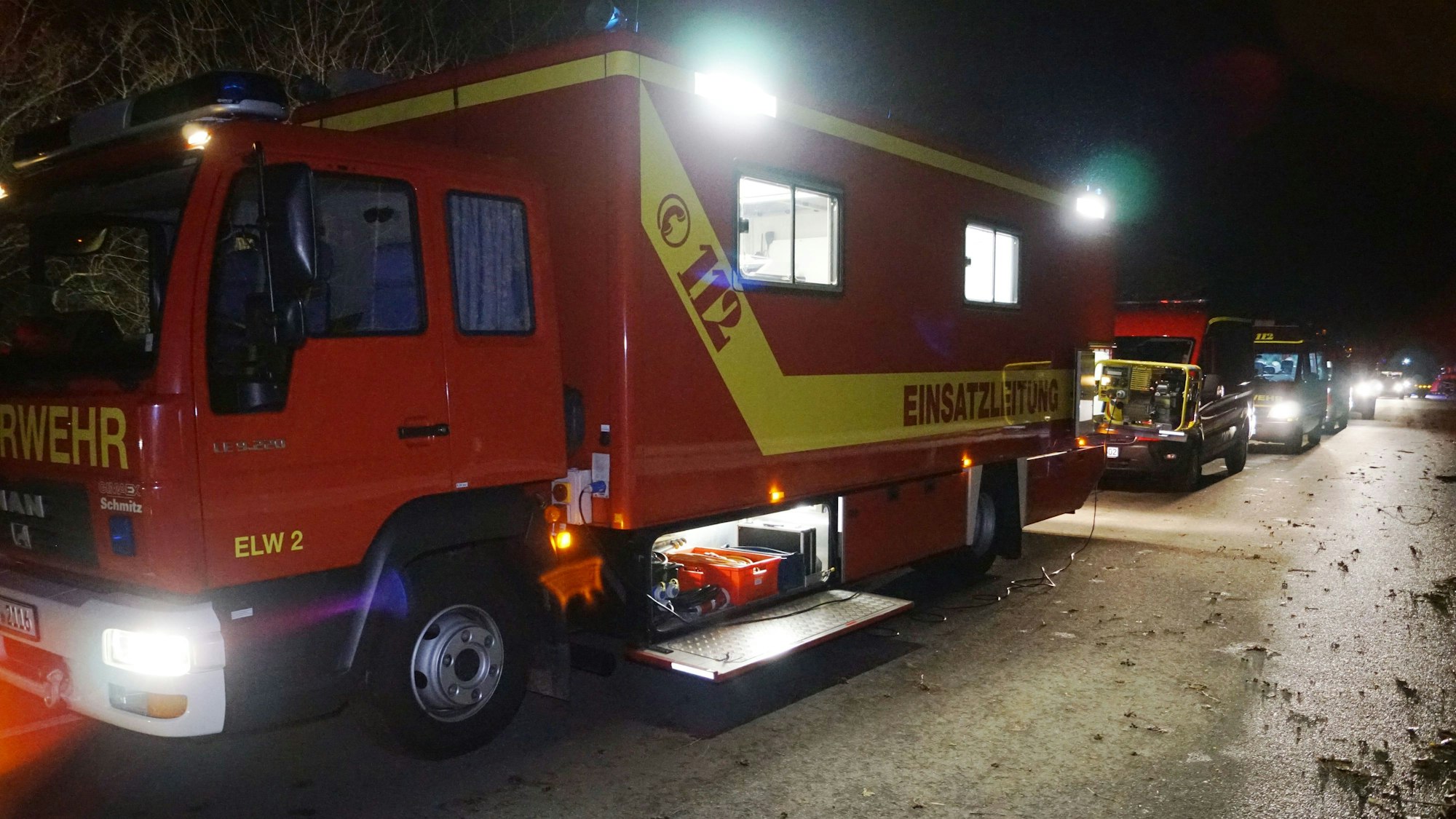 Mehrere Feuerwehrfahrzeuge stehen in der Dunkelheit auf einem Sammelplatz, von wo aus sie zu einem Einsatz im Ruhrgebiet aufbrechen.