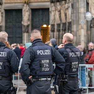 Köln: Wegen eines befürchteten Anschlags kontrolliert die Polizei alle Besucher des Doms. Zu sehen sind die Hinteransichten von vier Polizisten vor dem Hauptportal des Doms.&nbsp;