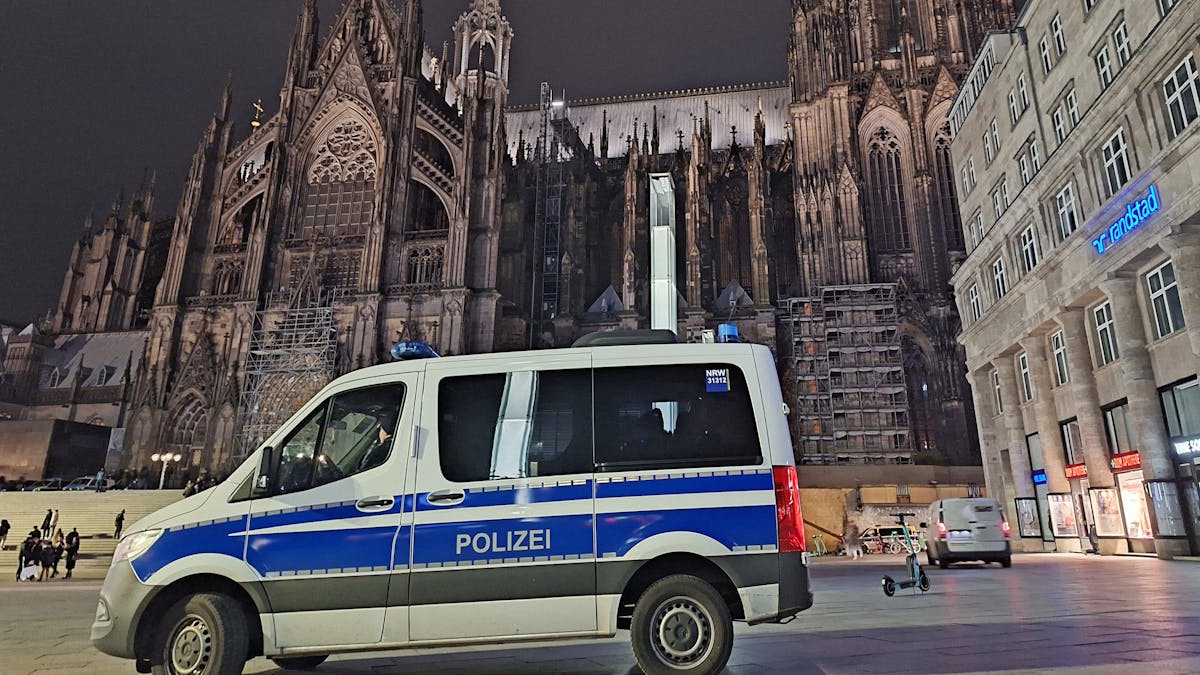 Ein Einsatzfahrzeug der Polizei steht in der Dunkelheit vor dem Kölner Dom.&nbsp;