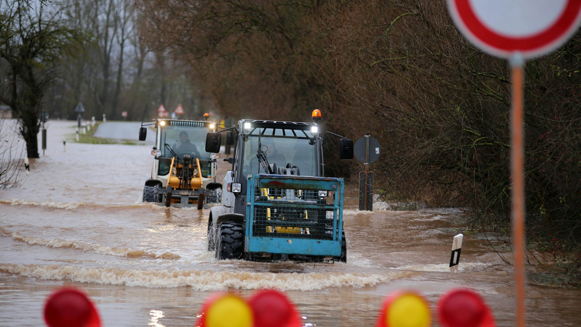 Zwei Traktoren verlassen den Ort Windehausen über eine von Hochwasser überflutete Straße.