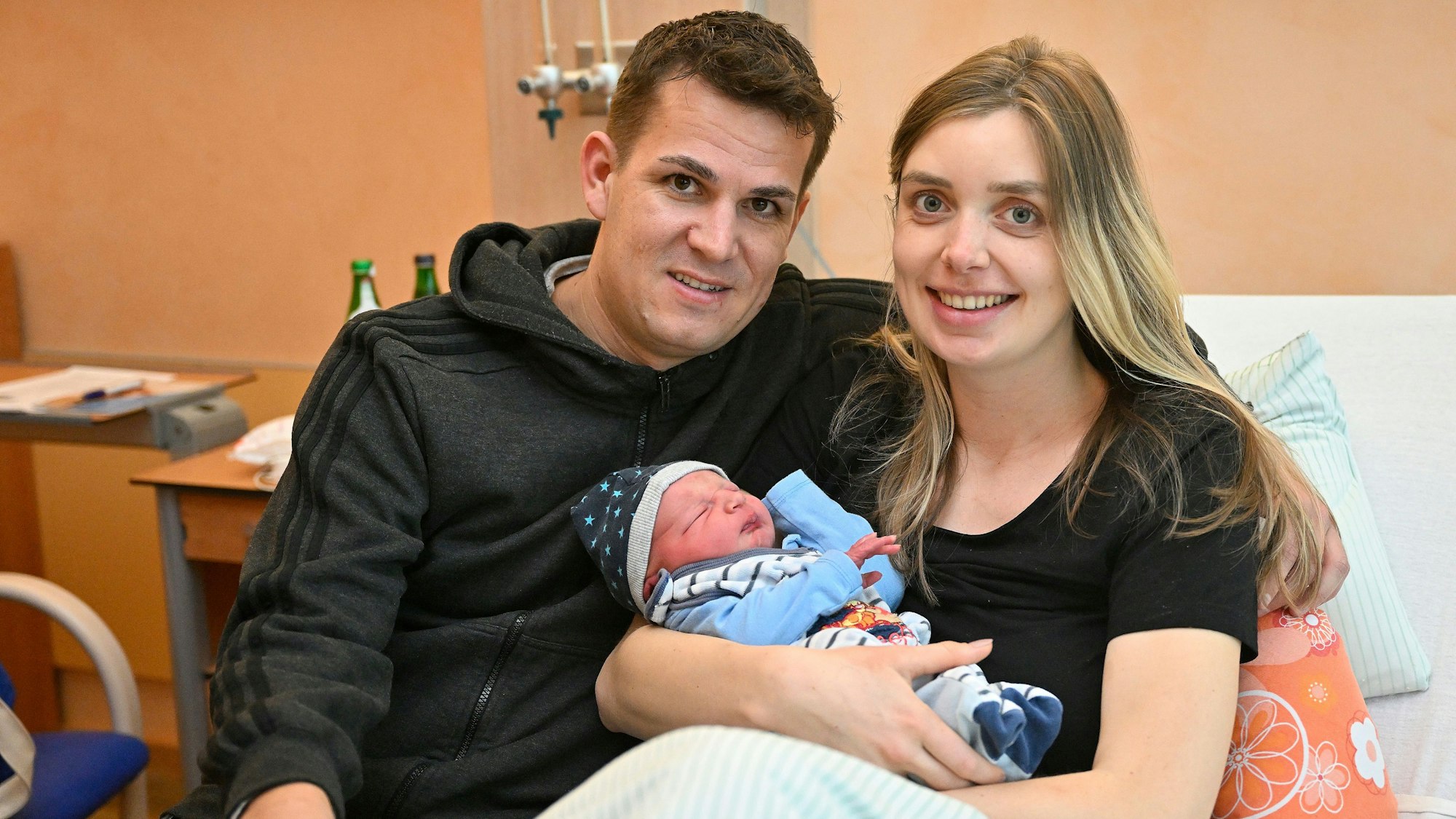 Marie Duske und Helge Hohl sitzen mit ihrem frisch geborenen Sohn in einem Bett im Evangelischen Krankenhaus Bergisch Gladbach.