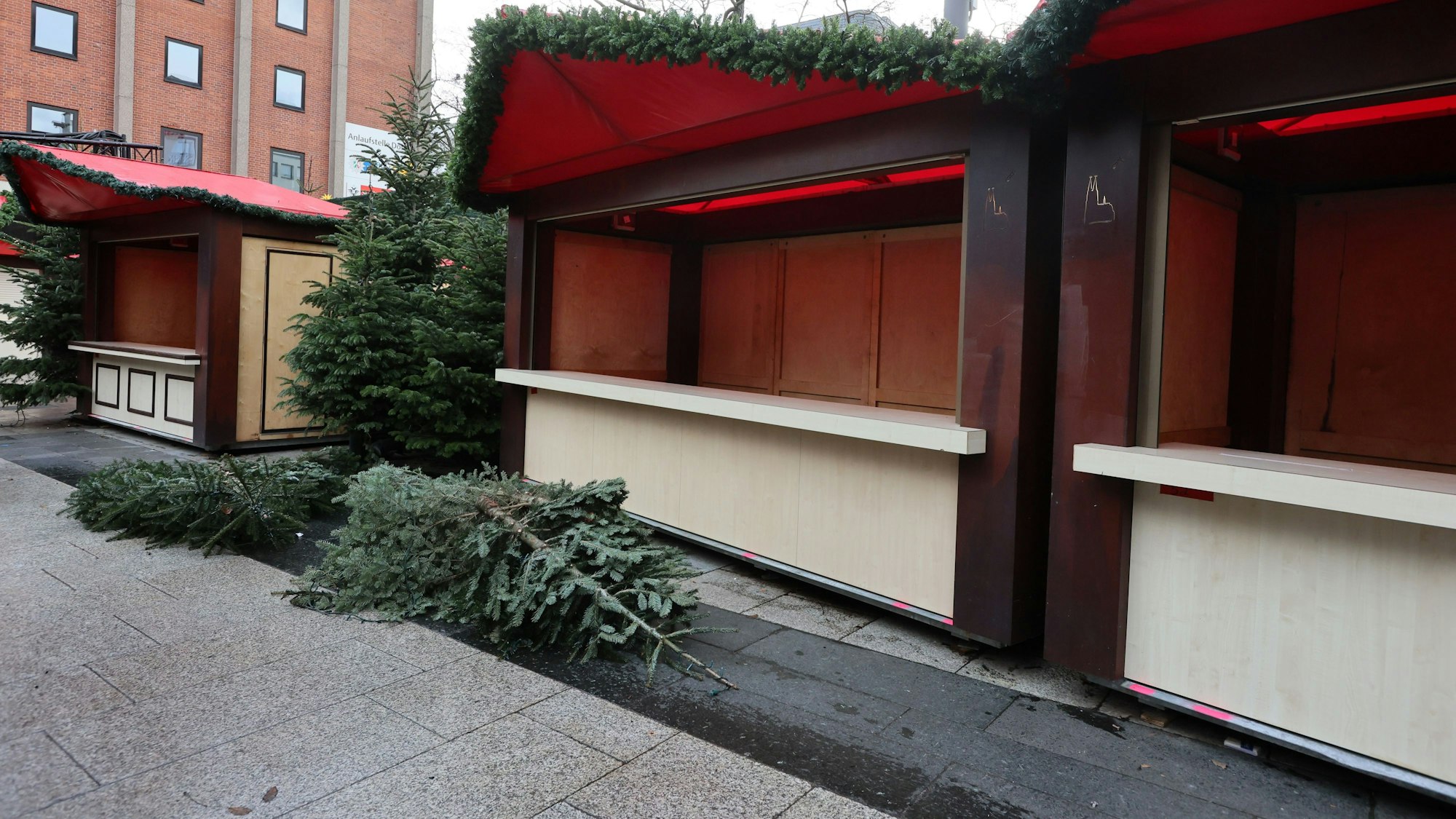 Weihnachtsbäume, die als Dekoration dienten, liegen auf dem Roncalliplatz vor den leer geräumten Hütten.

