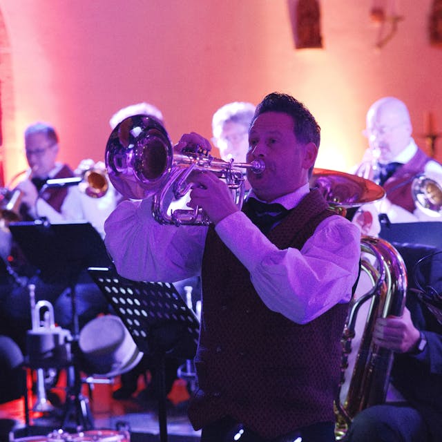 Ein Trompeter spielt in der Schwerfener Kirche. Im Hintergrund sind weitere Musiker zu sehen. 

