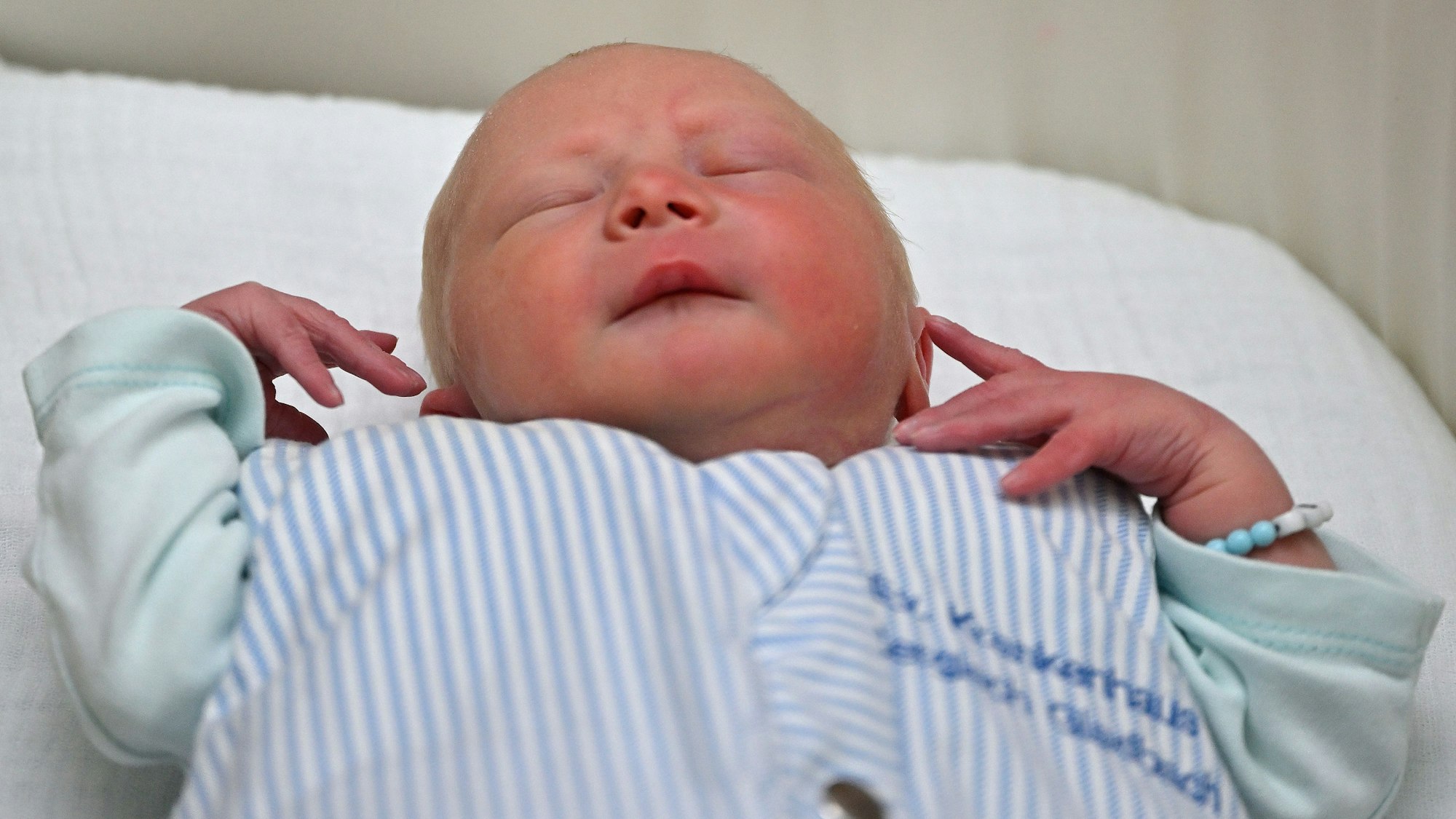 Ein Baby liegt in einem Strampler des evangelischen Krankenhauses Bergisch Gladbach in einem Bettchen.