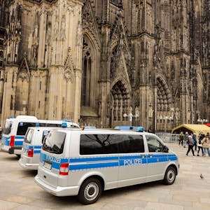 Mannschaftswagen der Polizei parken vor dem Kölner Dom.