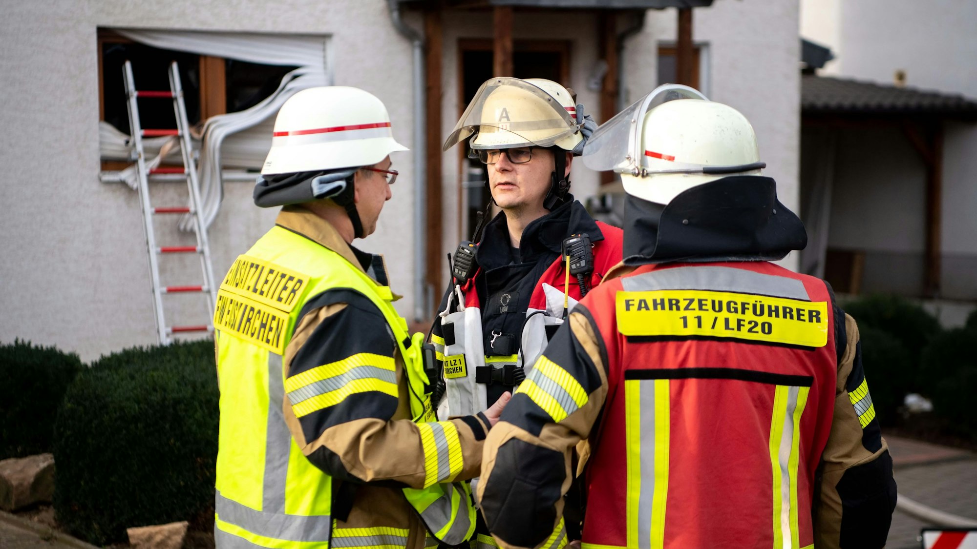 Das Bild zeigt drei Feuerwehrmänner, die den weiteren Einsatz besprechen.
