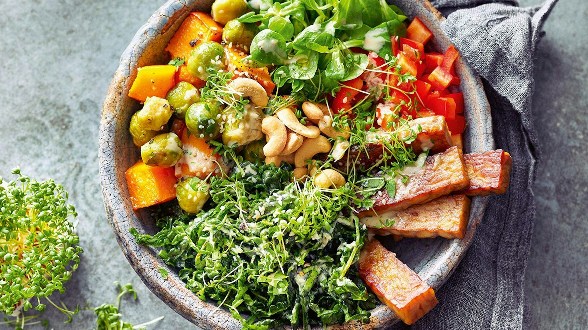 bunte Bowl mit Ofengemüse, frischen Grünkohlblättern und gebratenem Tempeh.