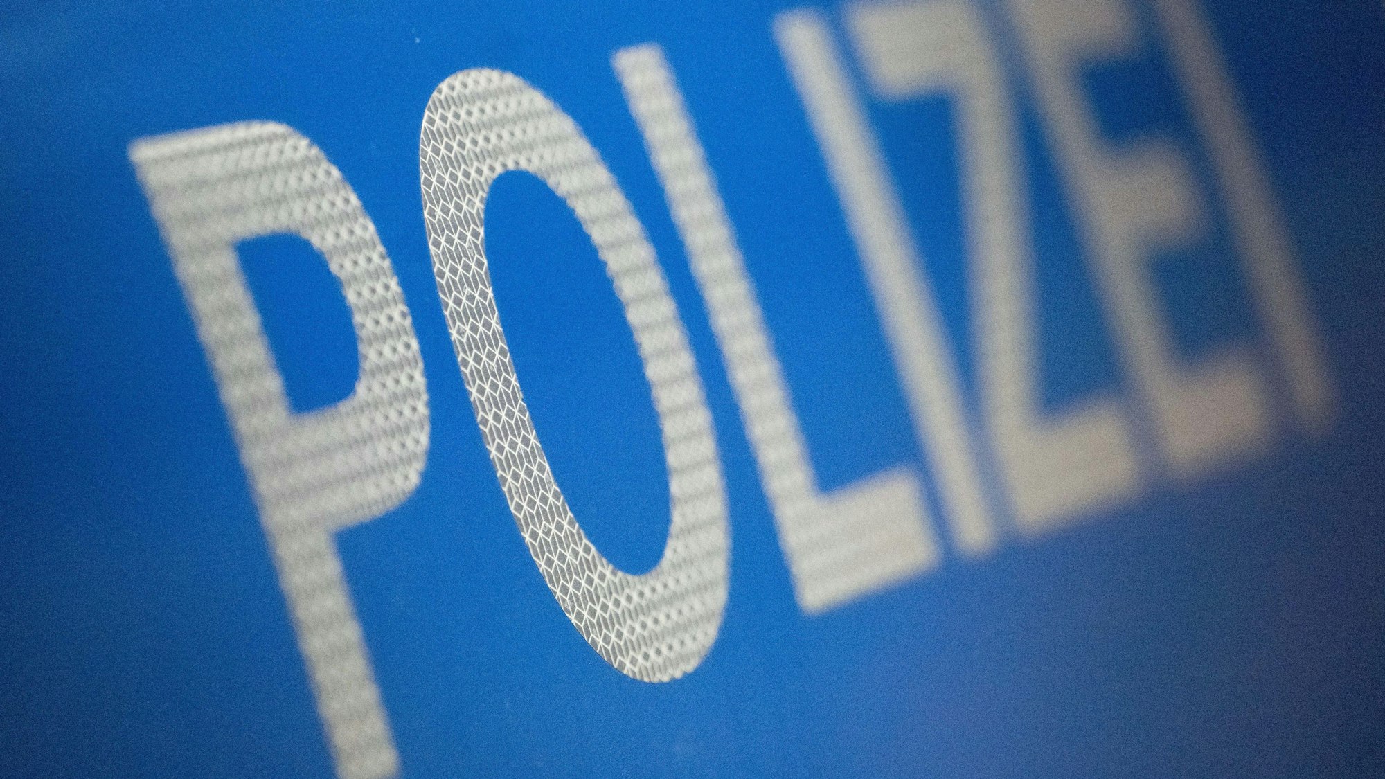 Das Wort Polizei ist im Rahmen eines Fototermins auf der Karosserie eines Polizeifahrzeugs zu sehen (gestellte Szene).