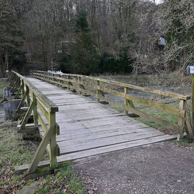 Zu sehen ist die Holzbrücke über die Sülz. Am Ufer rechts und links sind überspülte Wiesen.