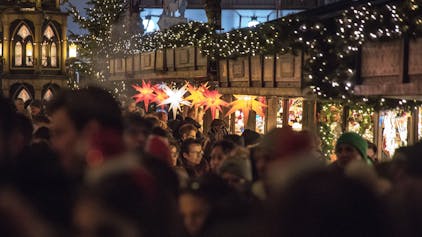 Menschen besuchen den Weihnachtsmarkt am Dom in Köln.