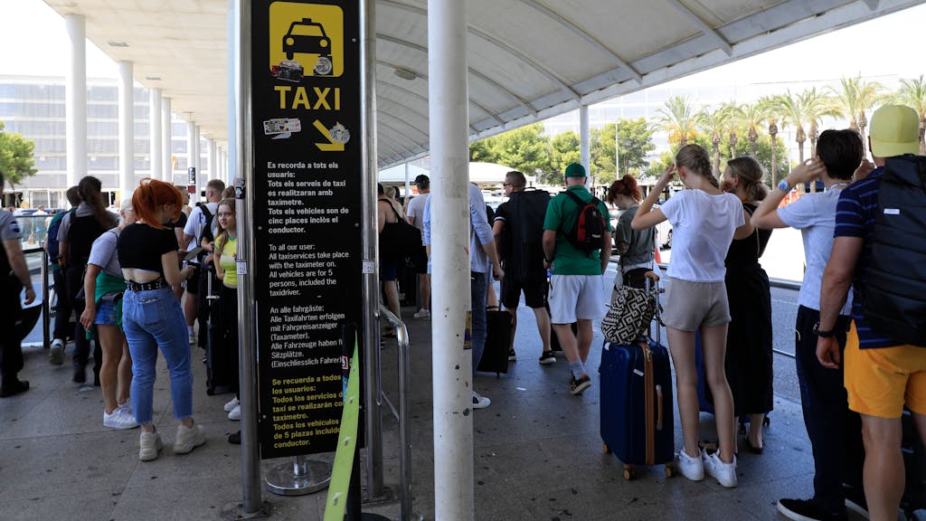 Reisende stehen am Flughafen von Mallorca in einer Schlange und warten auf Taxis.
