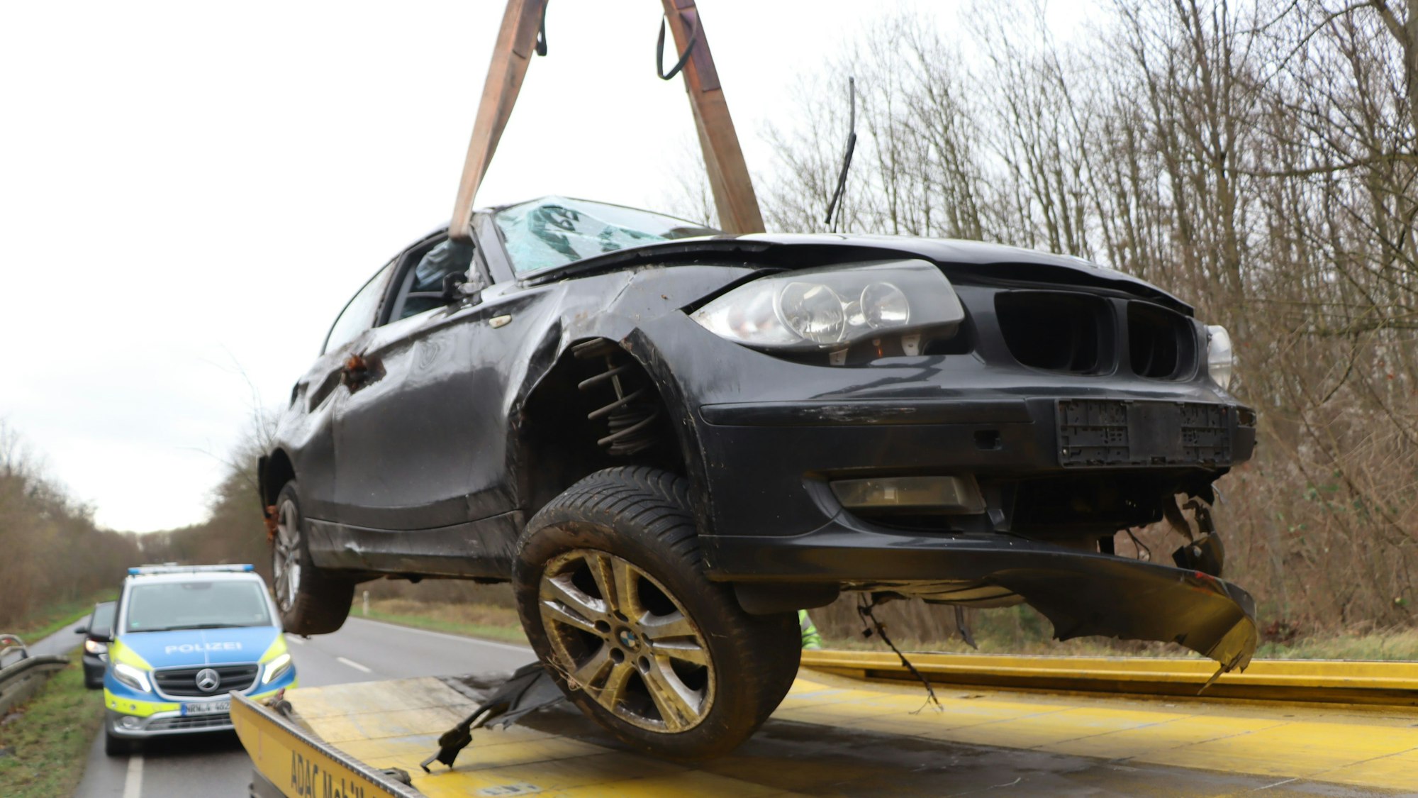 Ein bei einem Unfall schwer beschädigter BMW wird auf einen Abschleppwagen gehievt.