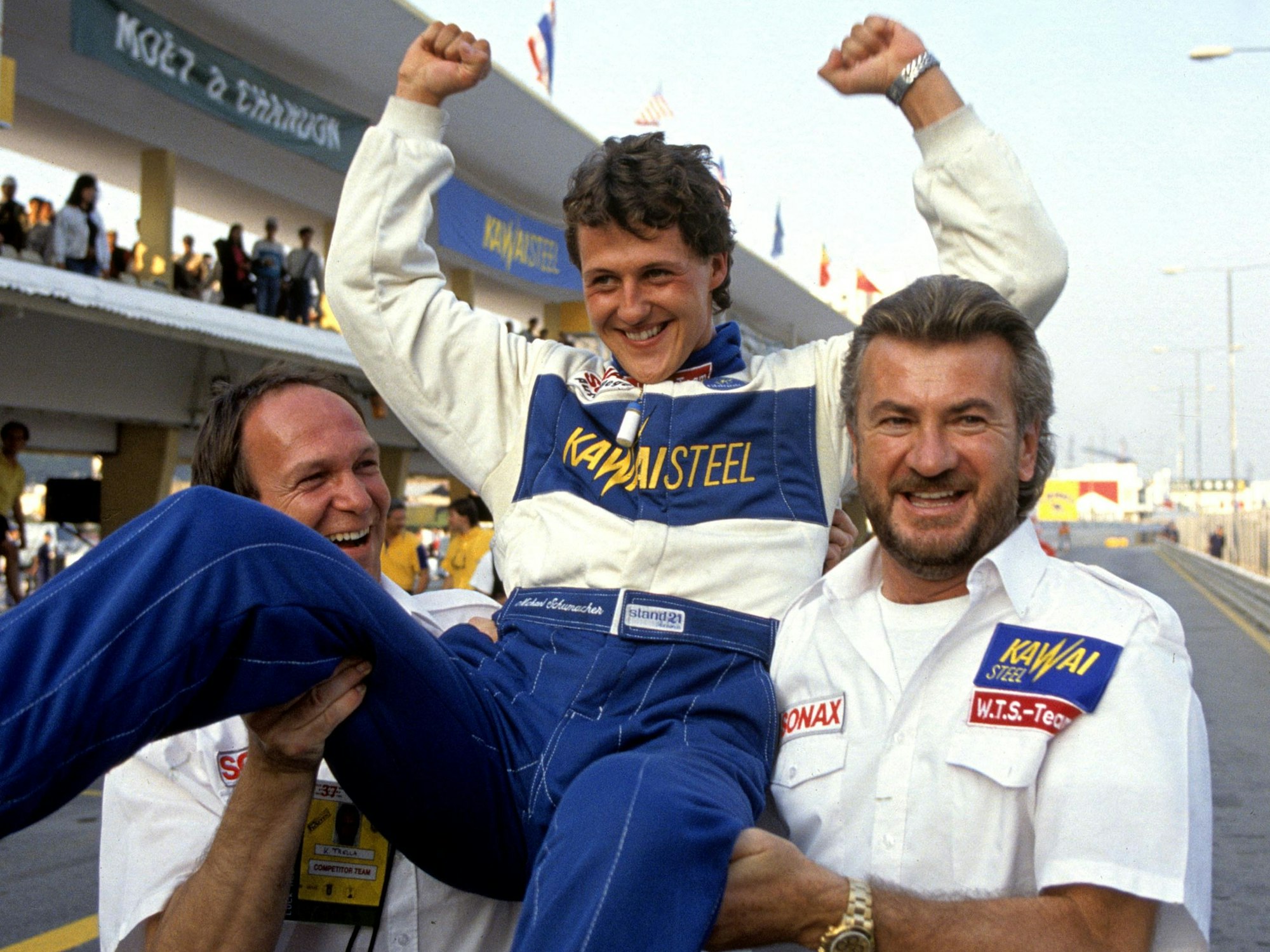 Franz Tost und Will Weber tragen Michael Schumacher jubelnd auf den Armen.