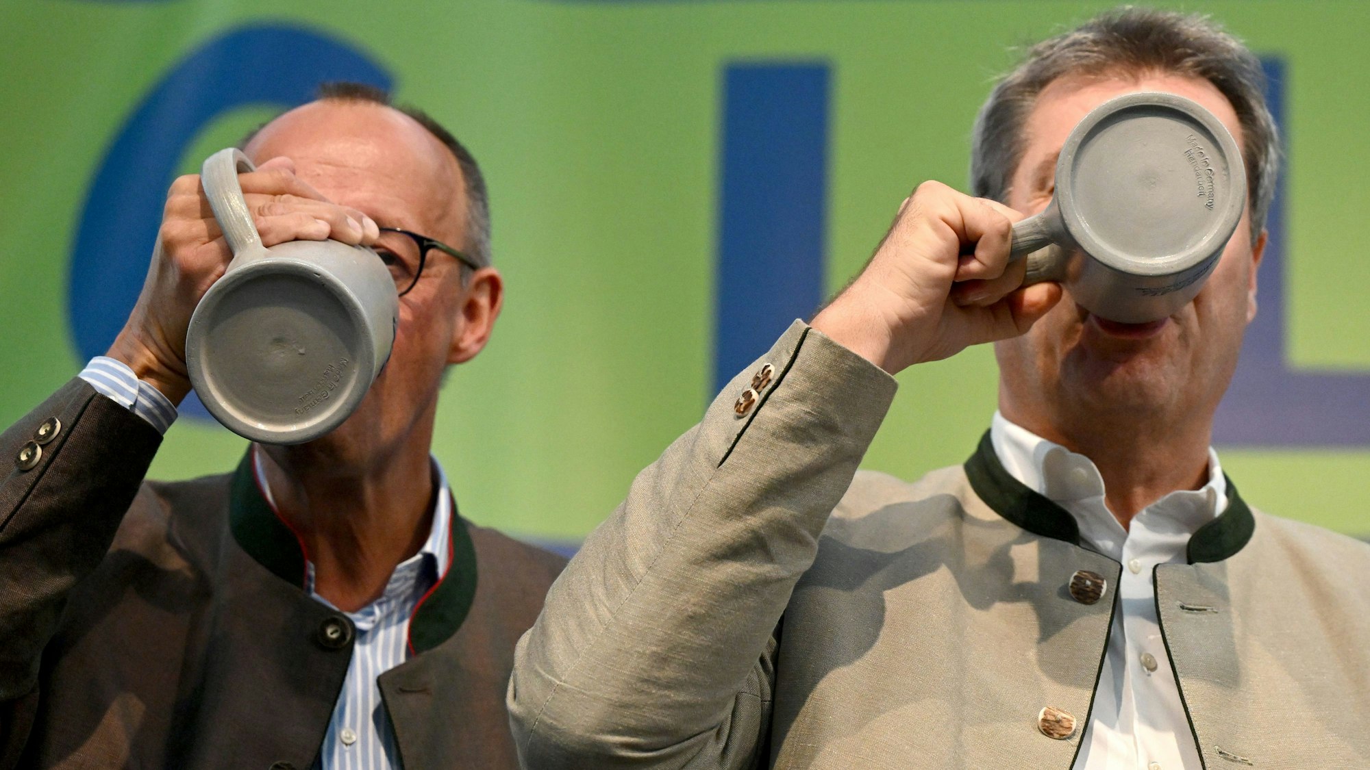 Bayern, Abensberg: Friedrich Merz (l), Bundesvorsitzender der CDU, und Markus Söder (CSU), Ministerpräsident von Bayern, trinken beim Politischen Frühschoppen Gillamoos auf der Bühne aus Bierkrügen.