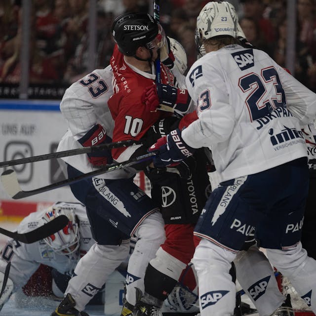 Mehrere Eishockeyspieler kämpfen dicht gedrängt um den Puck.&nbsp;
