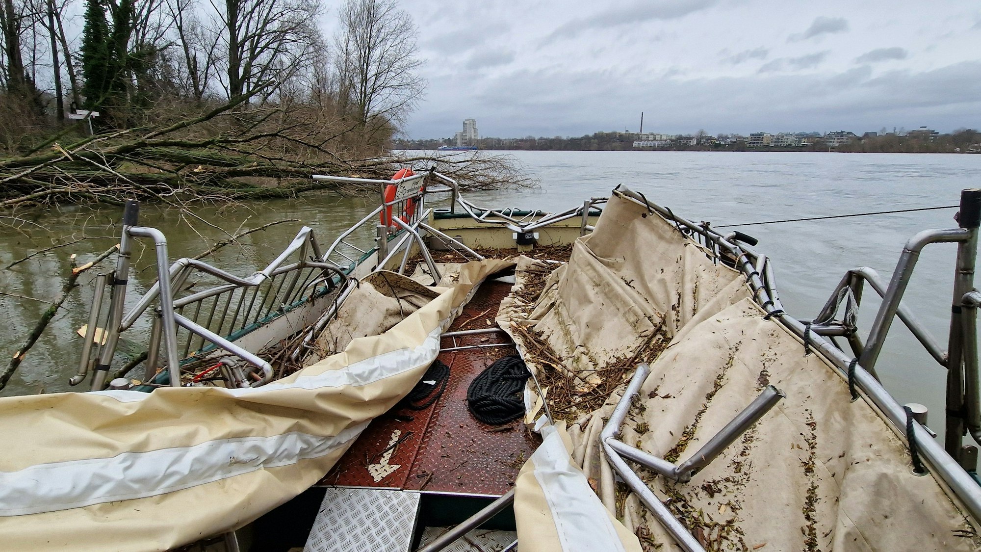 Das Dach der Fähre ist zerstört, die metallene Reling verbogen, am Ufer liegen umgeknickte Bäume halb im Wasser.