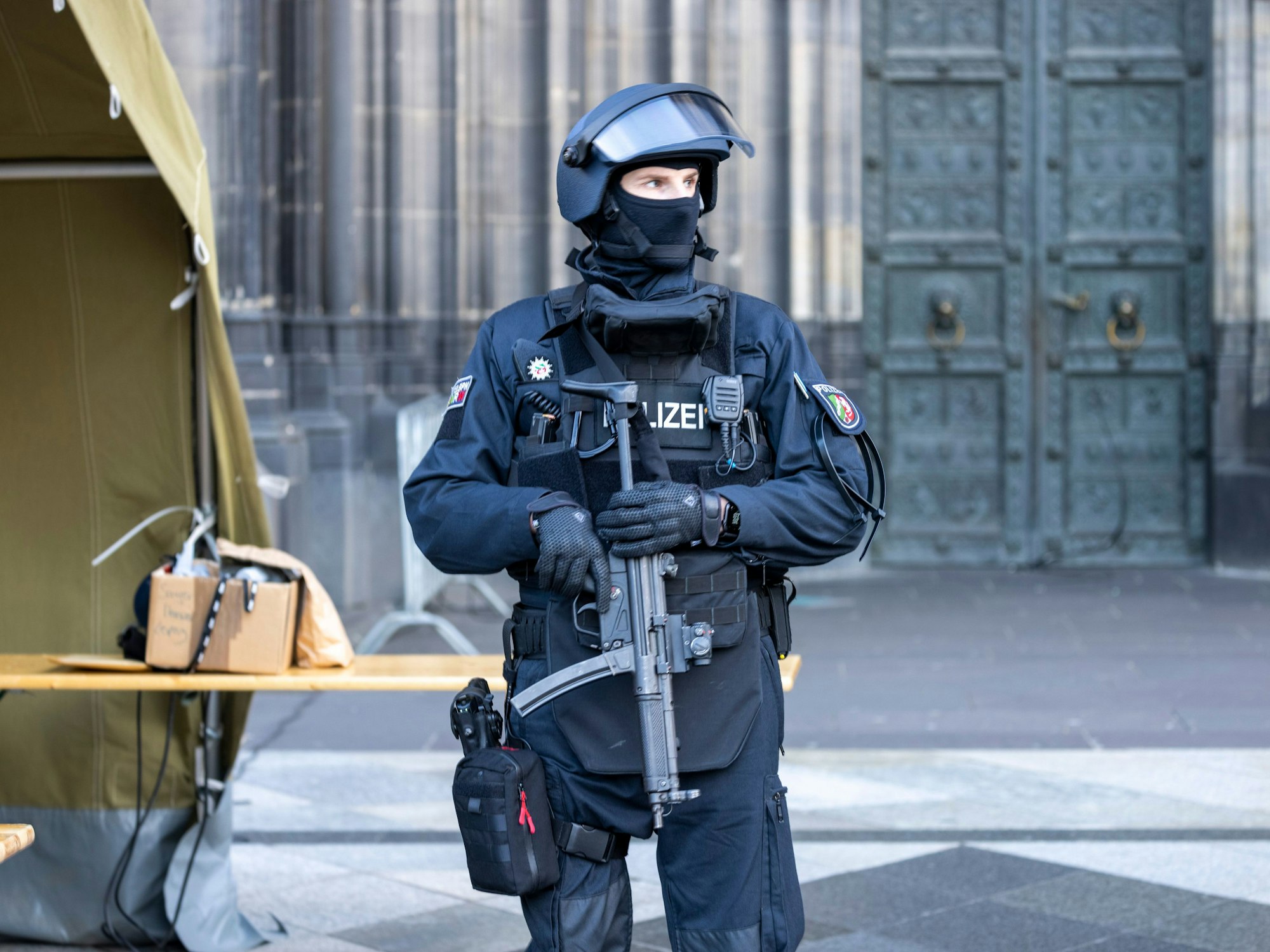 Ein Polizist mit Maschinenpistole steht vor dem Kölner Dom.