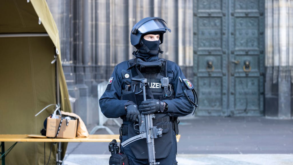 Ein Polizist mit Maschinenpistole steht vor dem Kölner Dom.&nbsp;