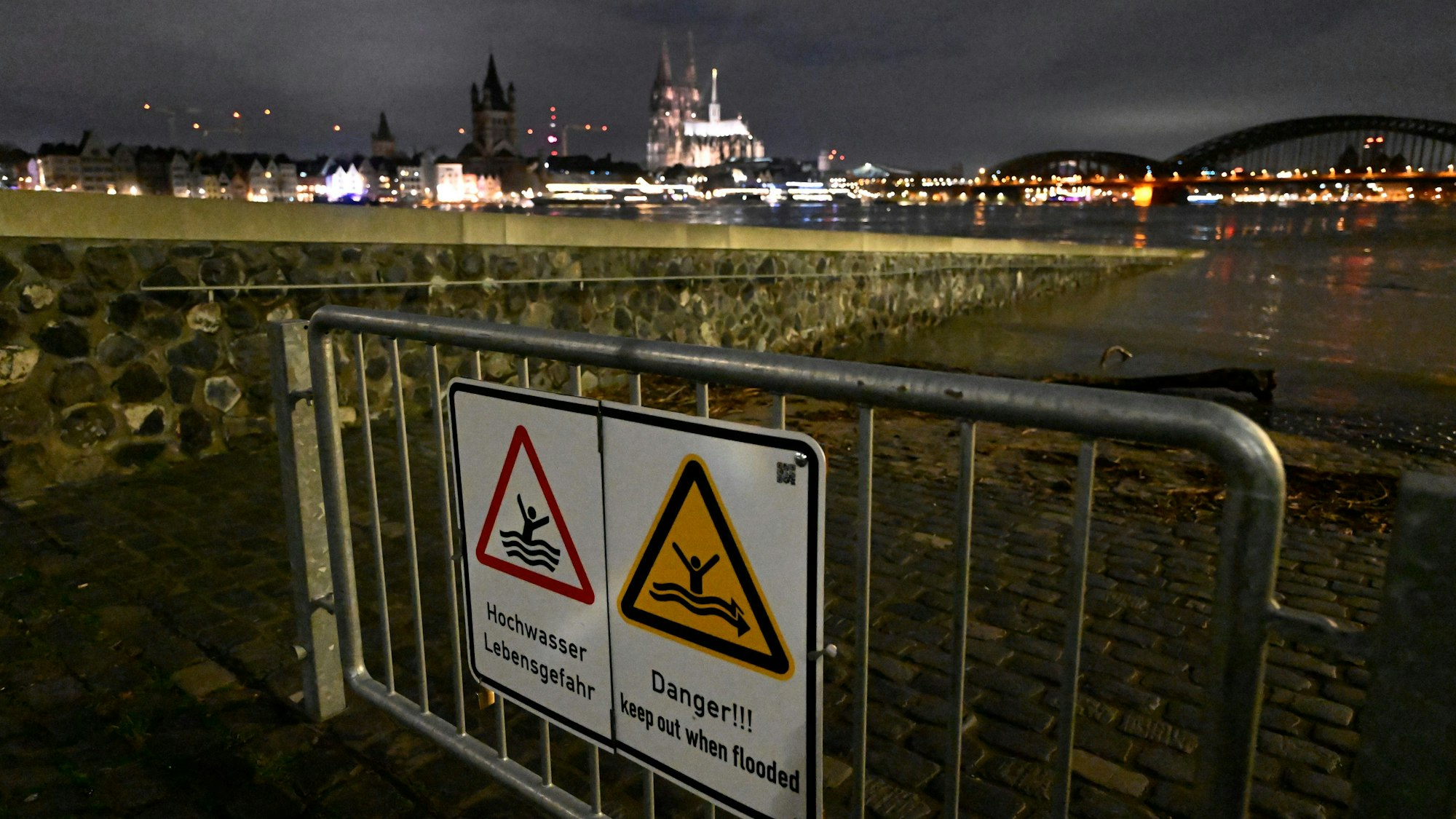 Hochwasser-Warnschilder sind am 27.12. am Rheinufer in Köln an einem Absperrgitter angebracht. Ergiebiger Dauerregen hatte den Pegelstand des Rheins ansteigen lassen, inzwischen ist er wieder deutlich gesunken. Doch es droht wieder Dauerregen.