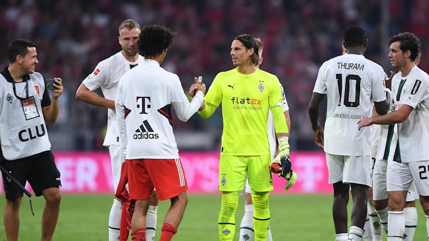 Spieler von Borussia Mönchengladbach klatschen nach Spielende mit einem Profi vom FC Bayern München ab.
