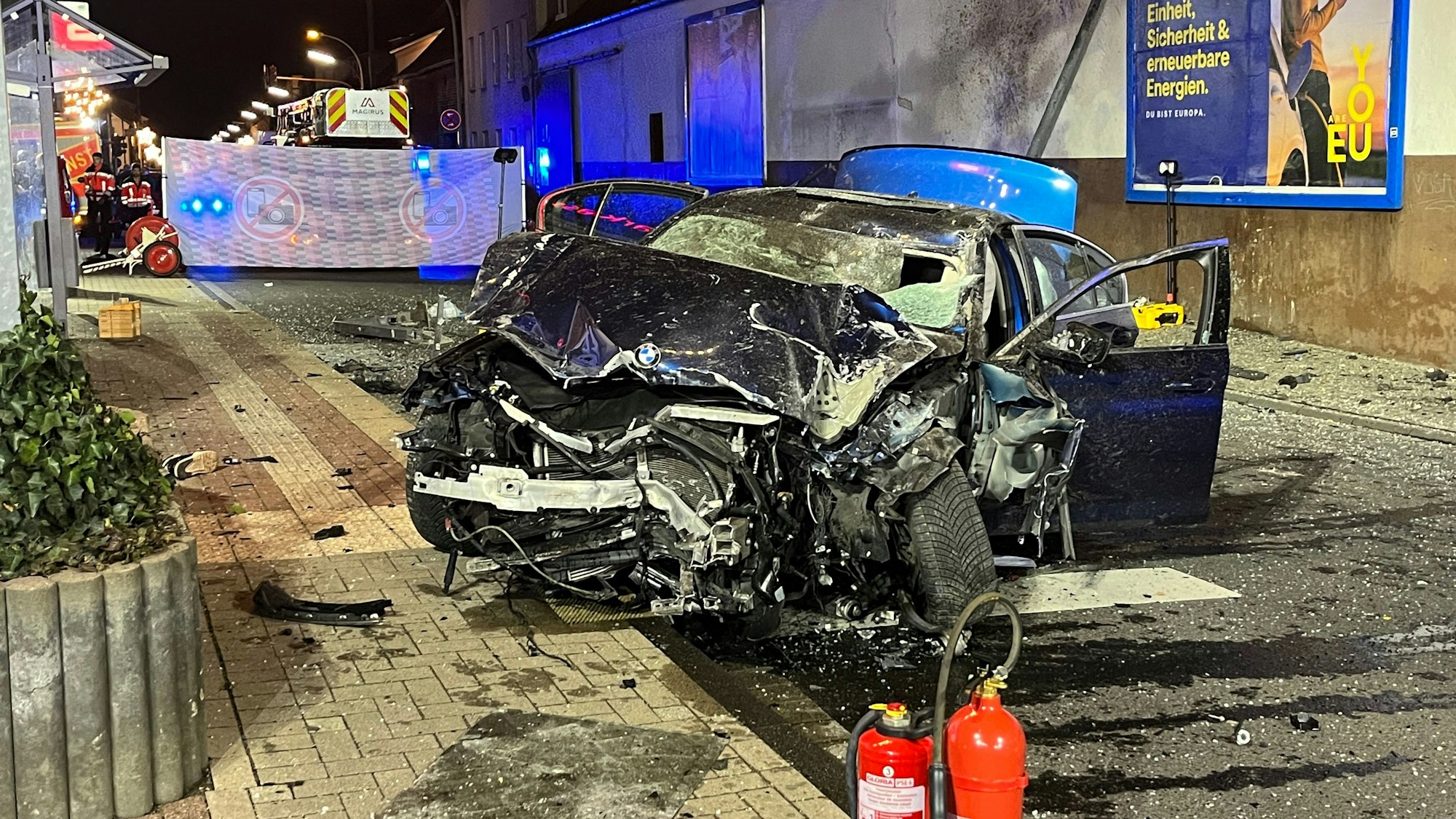 Auf der Provinzialstraße in Niederkassel-Mondorf steht der völlig zerstörte BMW, der ungebremst in eine Bushaltestelle gerast war und einen Jugendlichen tödlich verletzt hatte.