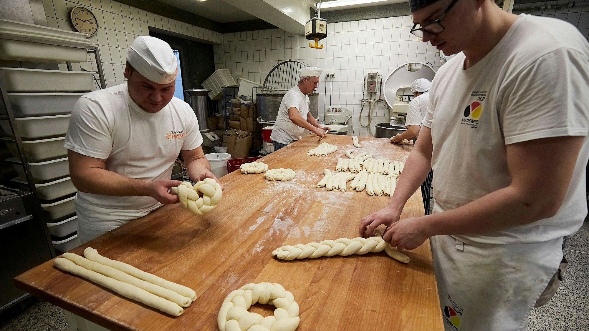 Das Bild vier Mitarbeiter der Bäckerei, wie sie gerade Neujahrskränze flechten.