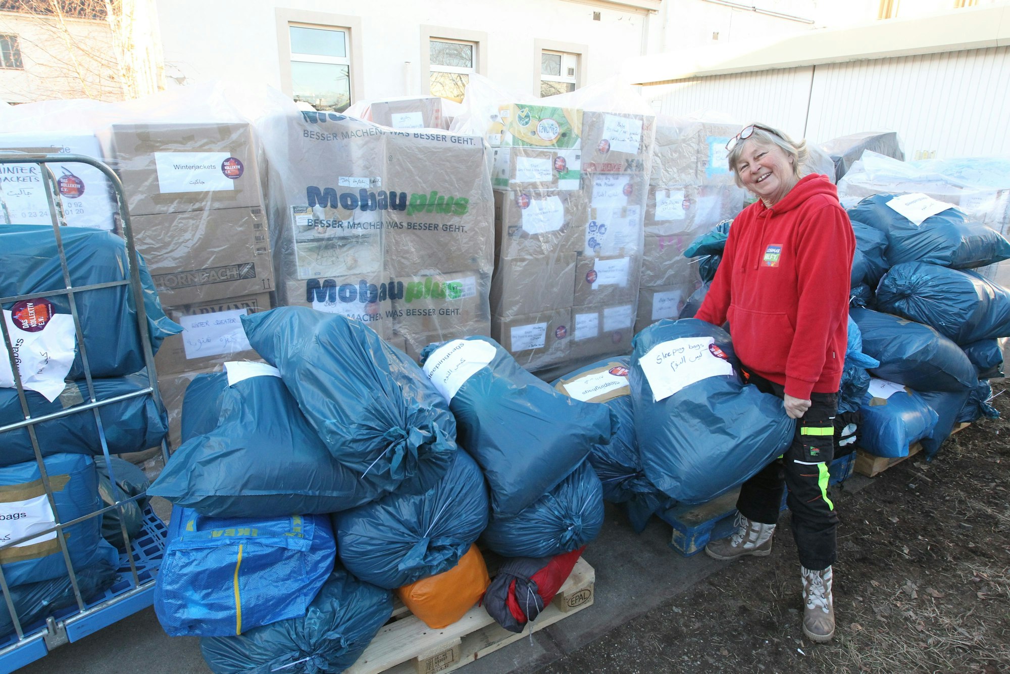Die Initiative Lohmar Hilft hat in Troisdorf Spich im Industriegebiet an der Gielichstraße riesige Mengen an Hilfsmittel angeliefert bekommen. Manu Gardeweg hat einen blauen Sack in der Hand.