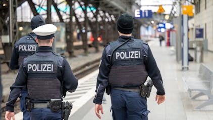 Zwei männliche Polizeibeamte patrouillieren auf Gleis 1 im Hauptbahnhof.