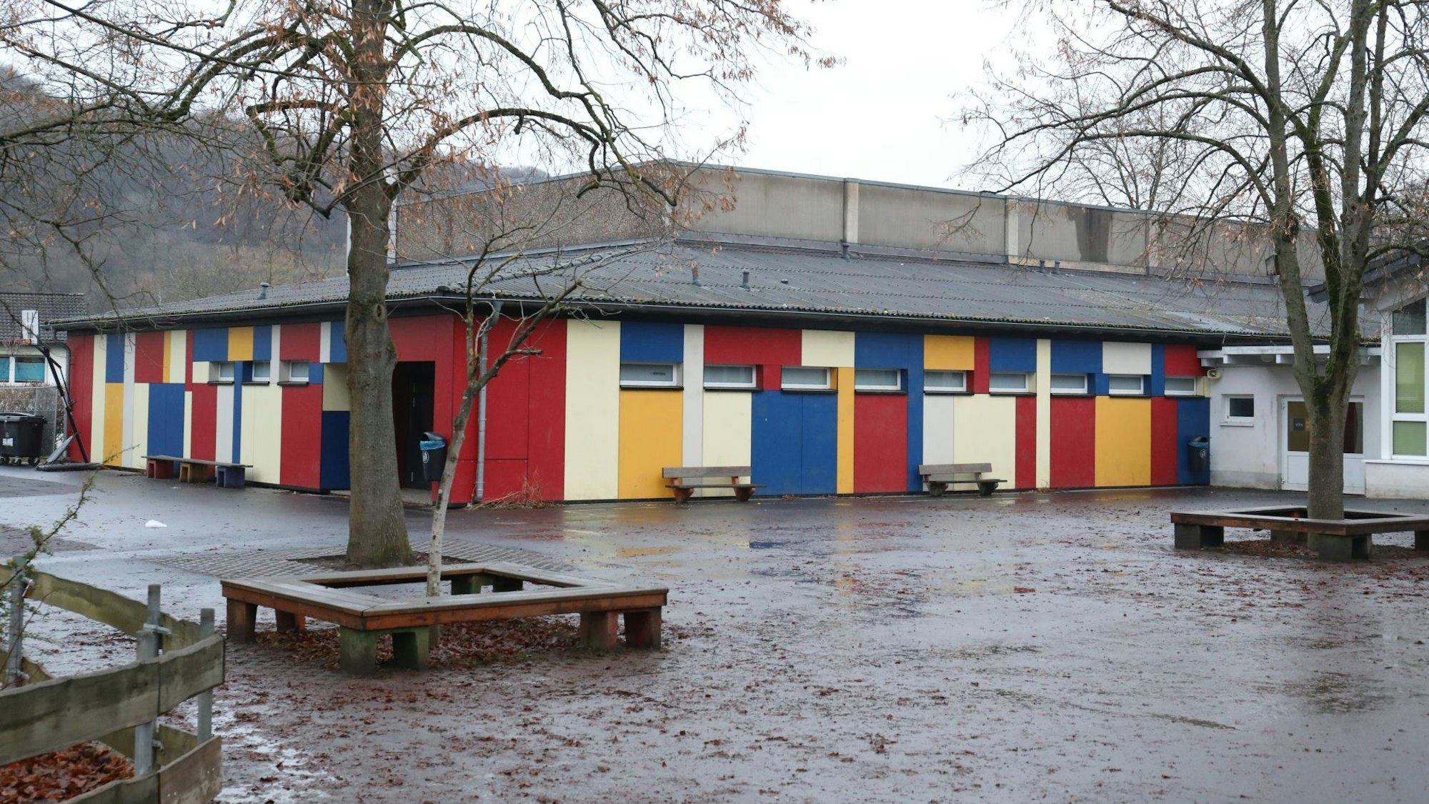Die Turnhalle der Grundschule Oberdollendorf hat eine bunte Fassade in den Farben Rot, Gelb, Blau und Beige.