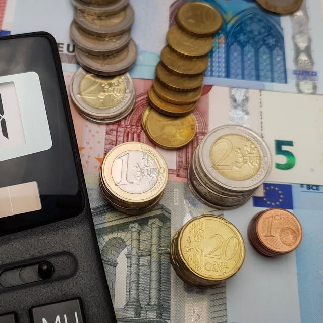 Ein Taschenrechner, auf dem 2024 steht, liegt auf verschiedenen Geldscheinen und -münzen