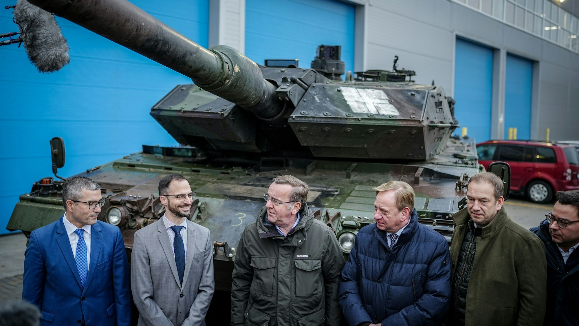 Boris Pistorius (M, SPD), Bundesminister der Verteidigung, steht am Instandsetzungshub Lithuanian Defence Services (LDS) mit Sebastian Dietz (2.vl) und Bundestagsabgeordneten vor einem Leopard 2 Panzer aus der Ukraine.