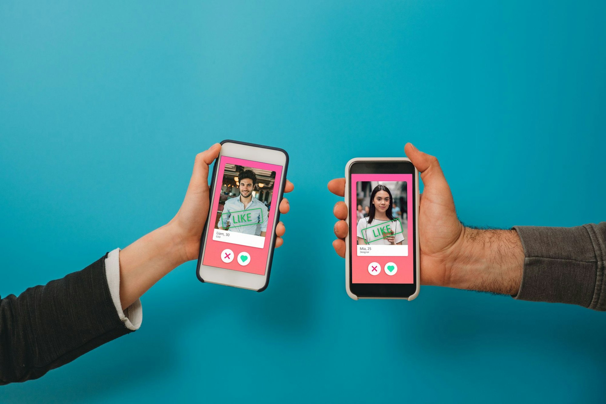 Conceptual image of two hands holding smart phones with an online dating app on the screen. Online dating app concept. Blue background.