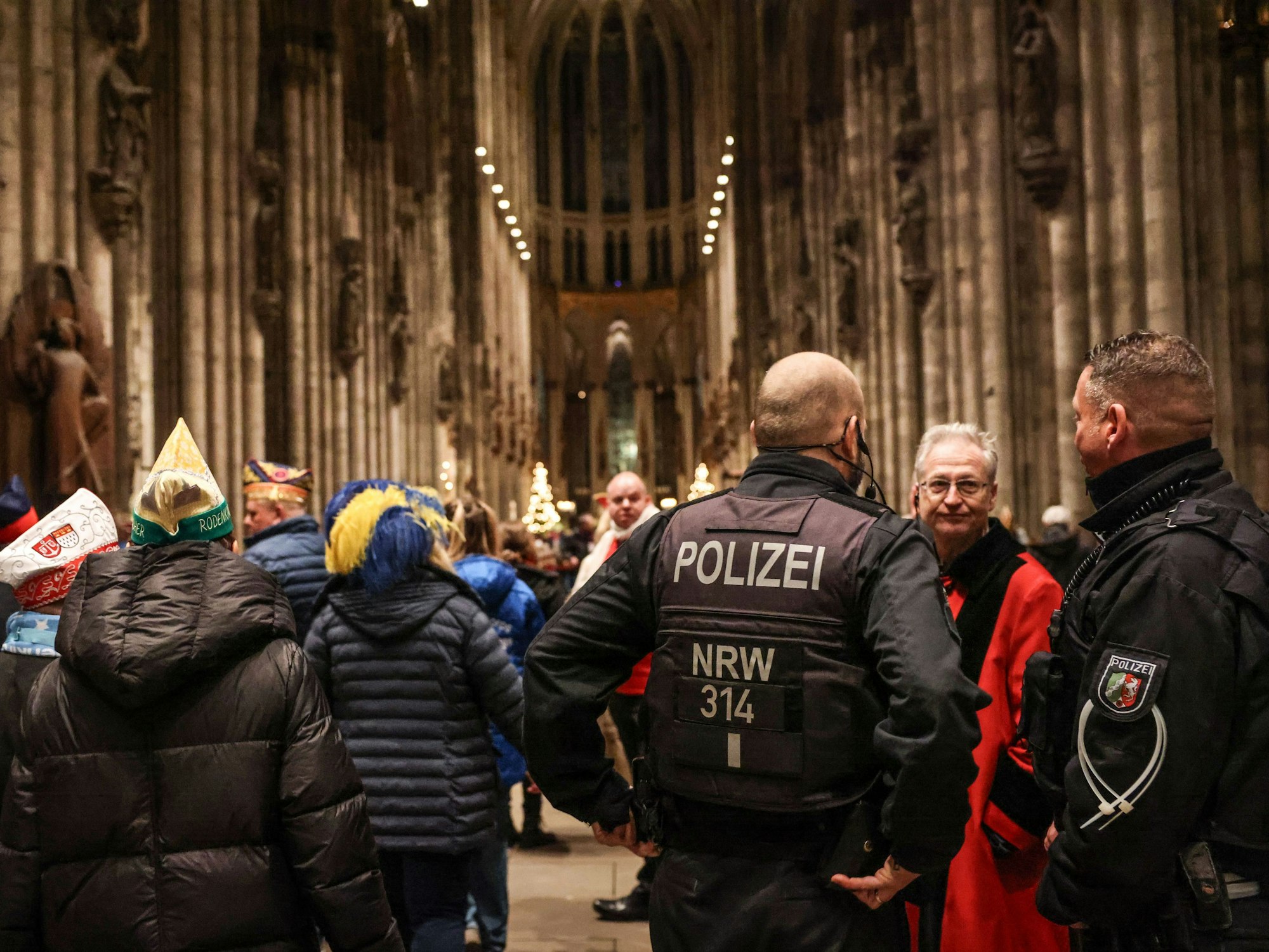 Polizisten stehen im Dom neben Karnevalistinnen und Karnevalisten. Verwendung nur bis zum 3. April 2024.