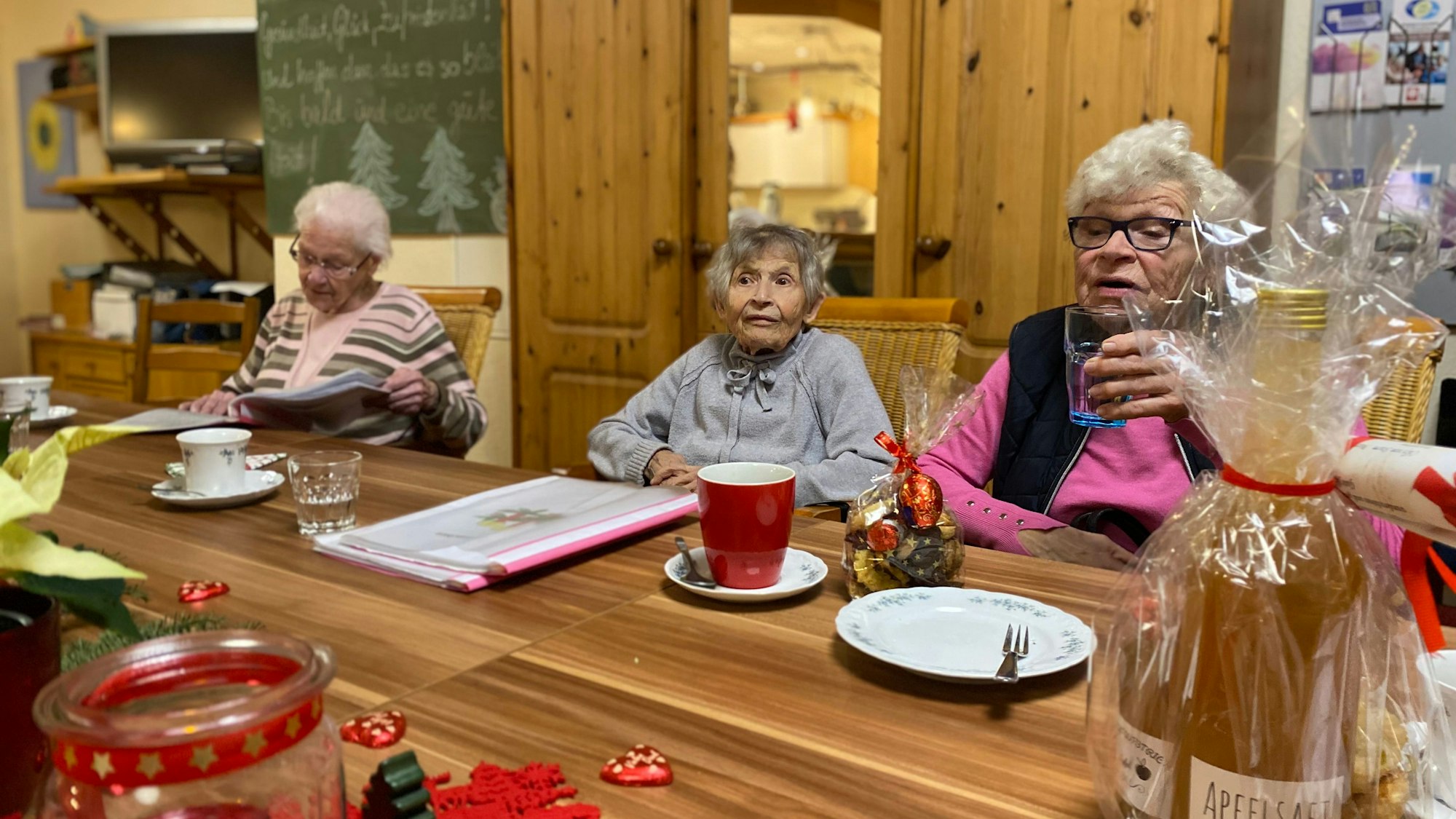 Die Besucherinnen des Demenzcafés sitzen gemeinsam an einem weihnachtlich geschmücktem Tisch.