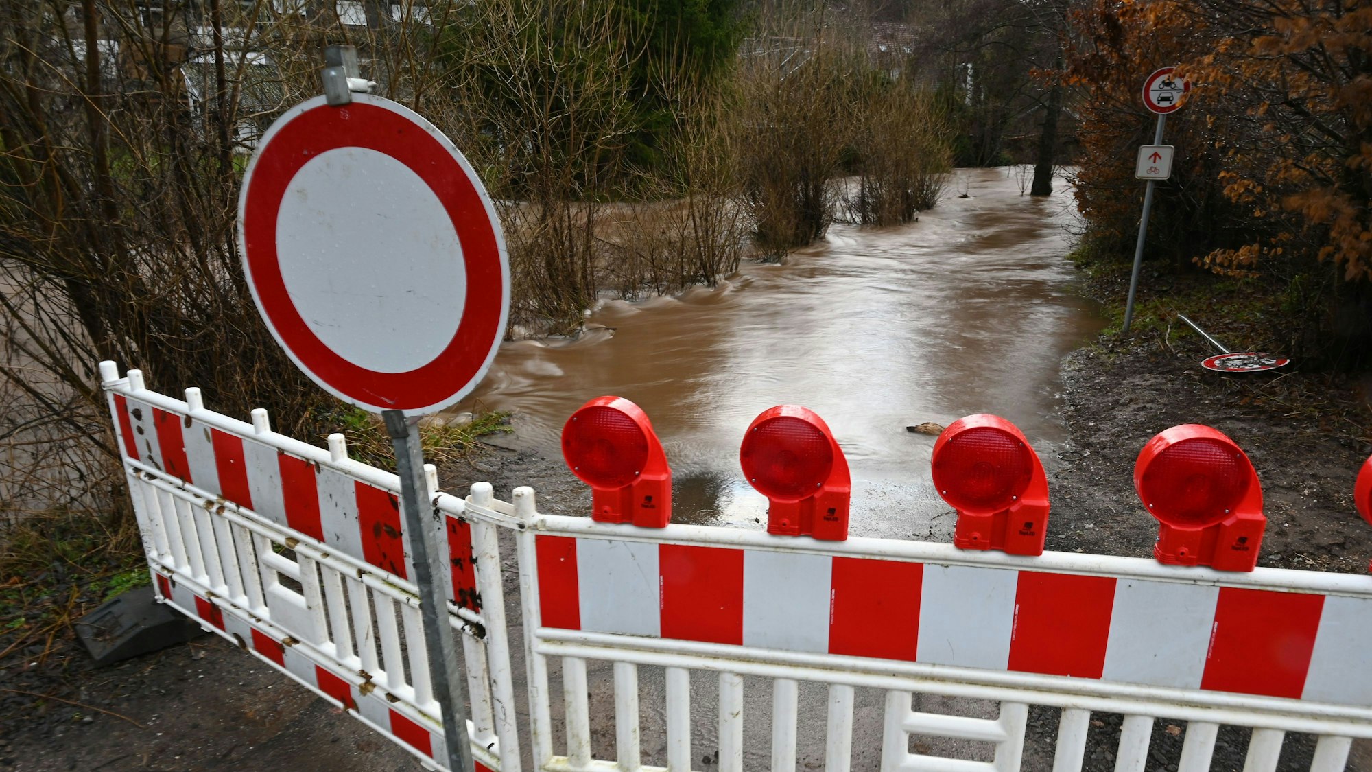 Eine Absperrung hat die Feuerwehr vor einem Radweg angebracht. Dieser ist vom Wasser der Olef in Oberhausen überflutet.