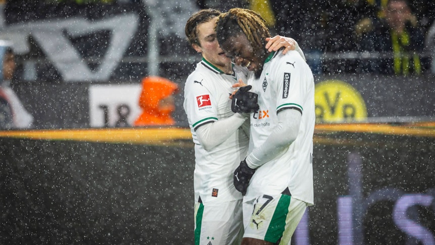 Rocco Reitz und Manu Kone schlagen im Dortmunder Stadion miteinander ein. Es regnet.