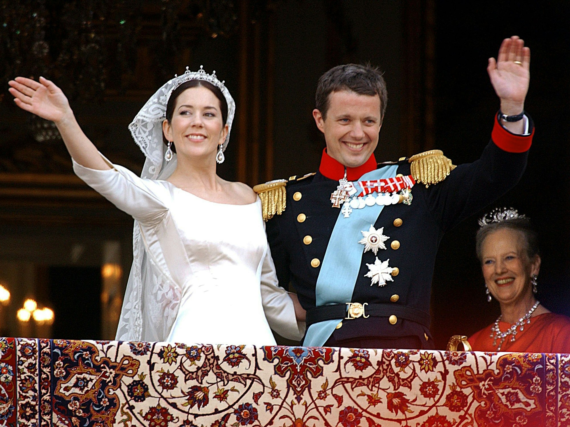 Der dänische Kronprinz Frederik (r) und seine frisch angetraute Frau Prinzessin Mary am Freitag (14.05.2004) auf dem Balkon von Schloss Amalienborg der Menge zu. Rechts im Hintergrund die dänische Königin Margrethe.