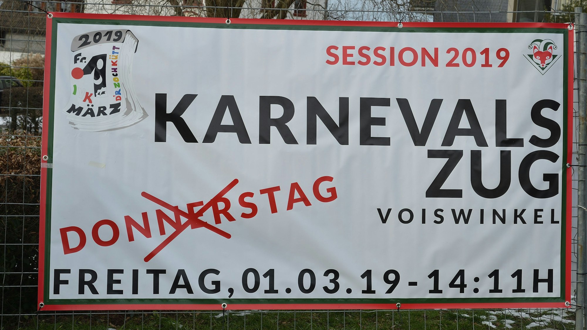 Ein Schild kündigt an, dass der Karnevalszug Voiswinkel 2019 nicht am Donnerstag, sondern am Freitag stattfindet.